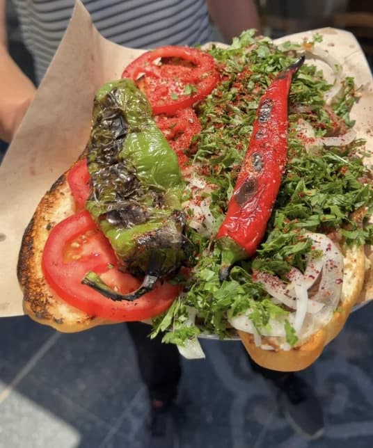 Ekmek arası sütlü kavurma; domates, közlenmiş biber, soğan ve maydanozla